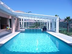 a large swimming pool in the middle of a house with an enclosed patio and sun room