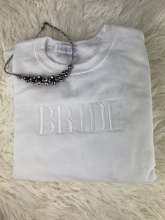 a white t - shirt with the word bride on it and a beaded necklace