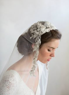 a woman wearing a veil with flowers and pearls on her head, in front of a white background