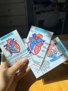 someone holding up two cards with the heart on them