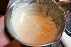 a hand holding a metal bowl filled with batter