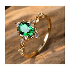 a gold ring with an emerald colored stone surrounded by white and clear diamonds on top