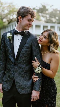 a man in a tuxedo standing next to a woman wearing a black dress