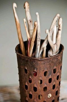 an old metal cup filled with sticks and cloves on top of a wooden table