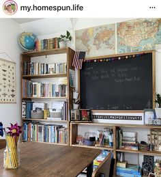 a wooden table sitting in front of a blackboard with writing on it and bookshelves