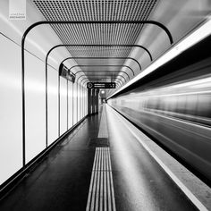 black and white photograph of a subway station with motion blurs in the foreground