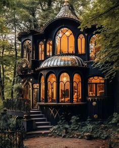 a black and gold house in the woods with stairs leading up to it's second story