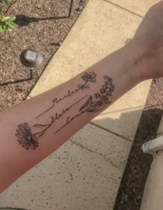 a person with a tattoo on their arm that has mountains and flowers in it,