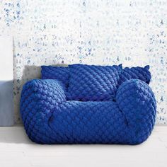 a blue bean bag chair sitting on top of a white floor next to a wall