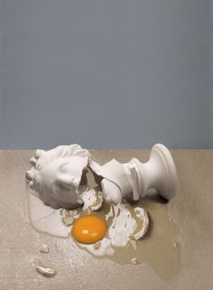 an egg laying on top of a table next to a statue