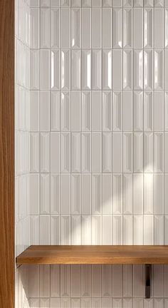 a wooden shelf sitting next to a white tiled wall