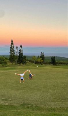 two people standing in the middle of a field with their arms up and one person holding a tennis racquet