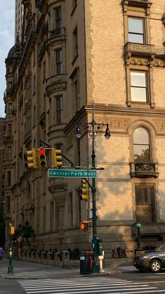 an intersection in front of a tall building with traffic lights and street signs on the corner