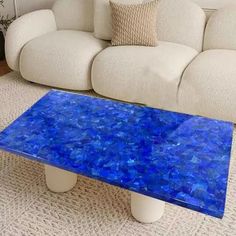 a blue table sitting on top of a carpeted floor next to a white couch