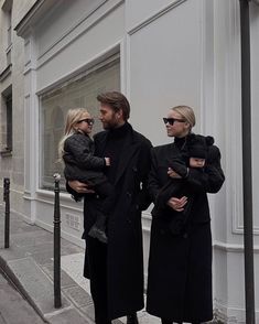 a man and woman standing next to each other in front of a building with two children