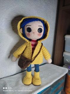 a crocheted doll wearing a yellow coat and boots