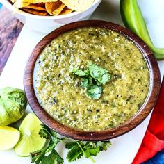 a bowl of guacamole next to a plate with chips and limes