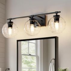 a bathroom vanity with three lights and a large mirror above it, in front of a window