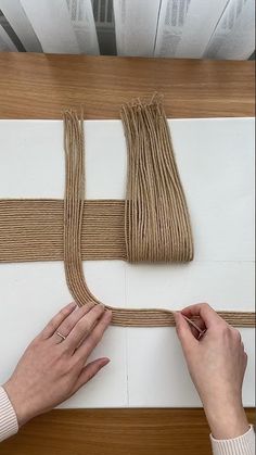 two hands are working on some string art