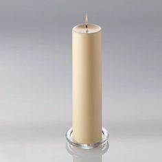 a white candle is sitting on a glass stand