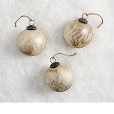 three ornaments are sitting on snow covered ground