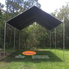 an outdoor tent set up in the middle of a field with trees and grass around it