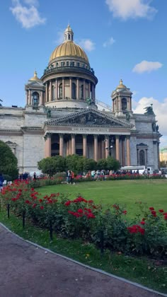 a large building with a golden dome in the middle of it's center surrounded by red flowers