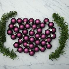 purple christmas balls are arranged in the shape of a heart on a marble table top