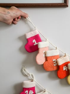 a person is hanging christmas stockings on a line with numbers and socks attached to it