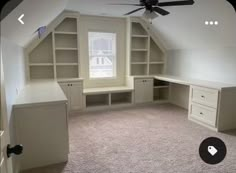 Interior photo of a room with a sloped ceiling and one window. There are built in shelves and two built in desks along the side walls. The desks and shelves are light gray, the ceiling is white, and the floor has beige carpet. Bonus Room Window Seat, Built In Desk Sloped Ceiling, Slanted Ceiling Office Ideas, Slanted Ceiling Built In, Built In Desk And Shelves Around Window, Knee Wall Built Ins, Finished Attic Storage, Bonus Room Office Combo, Bonus Room Built Ins