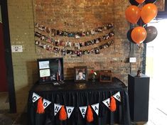 an orange and black party decoration with balloons, pictures, and photos on the wall