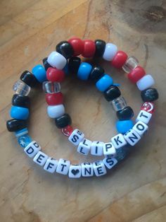 three bracelets with words on them sitting on top of a wooden table next to each other