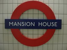 a sign that says mansion house on it in front of a wall with tiled walls