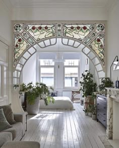 a living room filled with furniture and lots of plants on top of wooden flooring