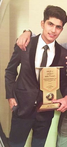 two men standing next to each other in front of a mirror holding an award plaque