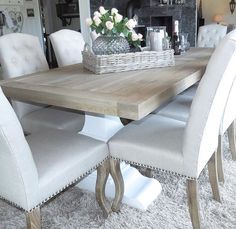 a dining room table with white chairs and a chandelier hanging from the ceiling