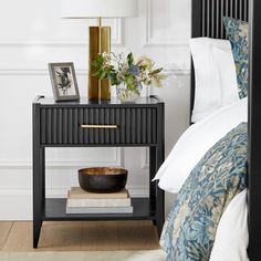 a nightstand with a bowl on it next to a bed