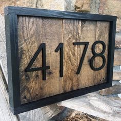 a wooden house number sign mounted to a stone wall