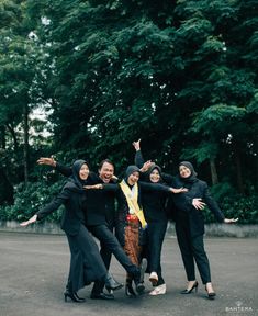 four women in black outfits are posing for the camera with their arms spread out and one woman is holding her hands up