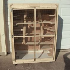 a large bird cage sitting on the side of a building next to a garage door