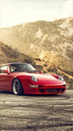 a red sports car parked in front of a mountain