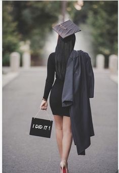 a woman walking down the street with a graduation cap on her head and holding a sign that says i did it