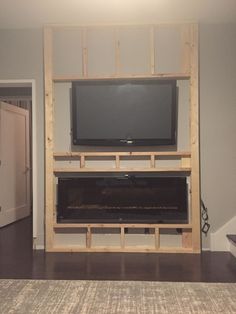 a flat screen tv mounted on top of a wooden entertainment center in a living room