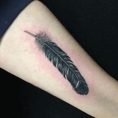 a black and white feather tattoo on the arm