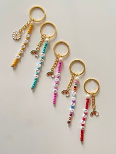 four keychains with beads and charms on them sitting next to eachother