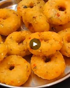 a metal plate filled with fried doughnuts on top of a table