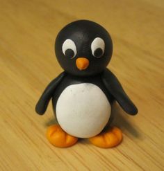 a small black and white penguin sitting on top of a wooden table