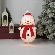 a snowman standing in front of a christmas tree