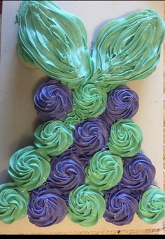 a cupcake shaped like a bunny with green and purple frosting