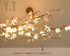 a chandelier hanging from the ceiling with white flowers on it's branches